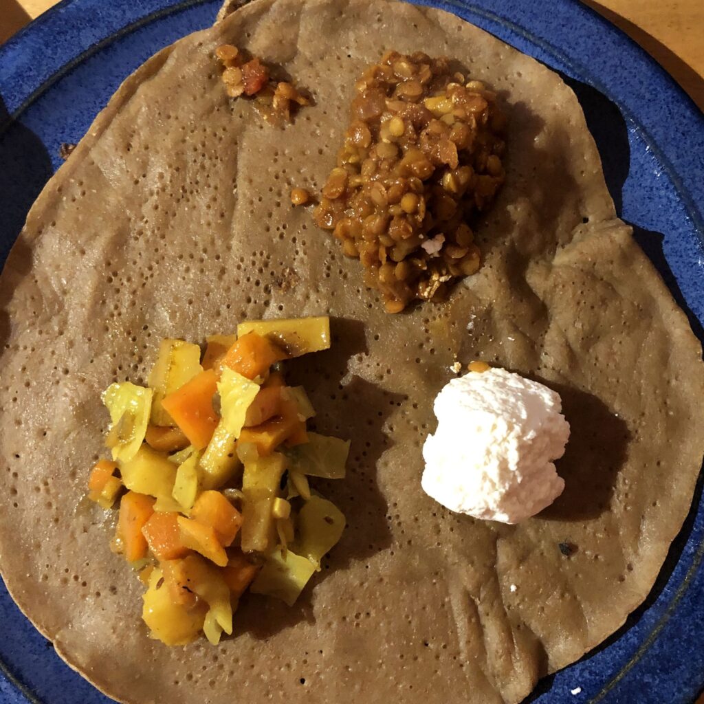 Teller mit Injera, Misir Wot, äthiopisch inspiriertem Kohl und Frischkäse