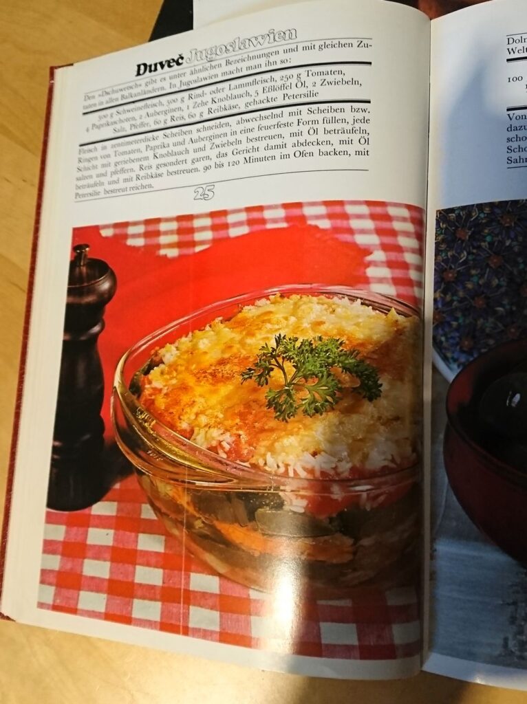 Rezeptseite Đuveč  aus "Die 100 berühmtesten Rezepte der Welt." Mit Kochanleitung und Đuveč-Schüsel vor rot-weiß karierter Tischdecke.